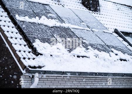 Panneaux solaires recouverts de neige sur le toit d'une maison à Essen, Allemagne Banque D'Images