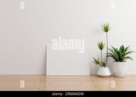 Maquette de cadre photo horizontal blanc sur un mur blanc pièce vide avec des plantes sur un plancher en bois Banque D'Images