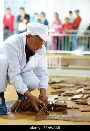 (171211) -- FU AN, 11 décembre 2017 -- un ouvrier ramasse des assiettes de sucre dans un atelier de sucre brun dans le village de Hongkou, dans le canton de Xitan à Fu an, dans la province du Fujian du sud-est de la Chine, 10 décembre 2017. Les gens ici utilisent la méthode la plus ancienne pour produire manuellement le sucre brun. Le jus de canne à sucre extrait de la canne à sucre est bouilli et agité en continu dans une casserole jusqu'à ce qu'il devienne sirop en quatre heures.) (dhf) CHINA-FUJIAN-FU AN-BROWN SUGAR (CN) WeixPeiquan PUBLICATIONxNOTxINxCHN Banque D'Images