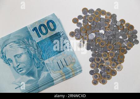 Plusieurs centaines de billets et pièces de monnaie reais du Brésil sur fond blanc neutre Banque D'Images