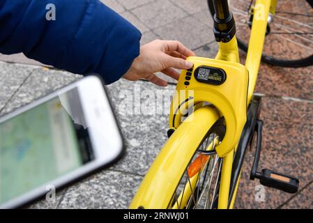 (171221) -- PARIS, 21 décembre 2017 -- le touriste Zheng Shaoming saisit un code pour déverrouiller un vélo Ofo à Paris, France, le 20 décembre 2017. Deux semaines après son lancement ici, l un des programmes populaires de partage de vélos en Chine, Ofo, vise à devenir le leader sur le marché en pleine croissance alors que la ville s efforce de promouvoir le transport vert pour réduire les émissions. Les vélos jaunes lumineux de la marque peuvent être trouvés à la fois dans des monuments emblématiques et des coins de rue tranquilles autour de la ville, et gagnent rapidement en popularité parmi les habitants et les touristes.) FRANCE-PARIS-CHINE-PARTAGE DE VÉLOS-OFO CHENXYICHEN PUBLICATIONXNOTXINXCH Banque D'Images