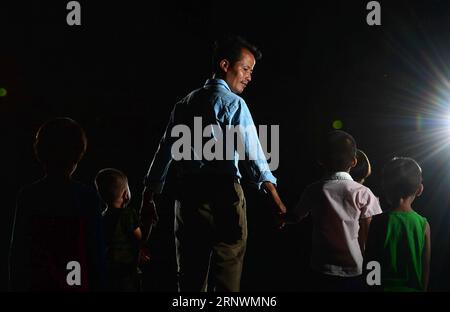 (171225) -- NANNING, 25 décembre 2017 -- Luo Feng, directeur de l'école primaire Bahao dans le canton de Bansheng, se tient avec des élèves du comté autonome de Dahua Yao, région autonome de Guangxi Zhuang, dans le sud de la Chine, 16 juillet 2017. Grâce aux politiques d'investissement menées ces dernières années, les installations de l'école ont été grandement améliorées. En raison des conditions environnementales difficiles telles que la désertification pierreuse et la forme montagneuse, Guangxi a longtemps été une région moins développée en Chine. Au cours des dernières années, les autorités locales ont effectué de nombreuses mesures pour les activités de réduction de la pauvreté. Des dizaines de milliers de fonctionnaires Banque D'Images