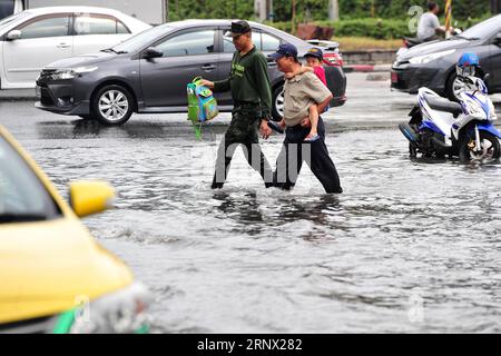 (180110) -- BANGKOK, 10 janvier 2018 -- Un soldat de l'armée thaïlandaise (L) aide un citoyen et son fils à traverser une rue inondée à Bangkok, Thaïlande, 10 janvier 2018. Un certain nombre de rues de Bangkok ont été inondées après que de fortes pluies aient frappé la capitale mercredi matin. (Whw) THAÏLANDE-BANGKOK-INONDATIONS URBAINES RachenxSageamsak PUBLICATIONxNOTxINxCHN Banque D'Images