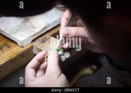 (180122) -- HANGZHOU, le 22 janvier 2018 -- Un artisan incrustation un bijou, conçu par Qian Zhongshu, avec du jade à Hangzhou, capitale de la province du Zhejiang de l'est de la Chine, le 22 janvier 2018. Qian est né en 1983 à Hangzhou. Passionné de culture traditionnelle chinoise, le diplômé de l'Académie chinoise des arts a démissionné de ses fonctions et a ouvert son propre atelier de bijouterie il y a environ neuf ans. Jusqu'à présent, son groupe compte près de 20 membres. Ils peuvent fabriquer plus de 300 bijoux chaque année. ) (Mcg) CHINA-HANGZHOU-Jewellery MAKER (CN) WengxXinyang PUBLICATIONxNOTxINxCHN Banque D'Images