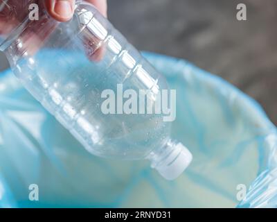 Responsabilité environnementale - la main de l'homme jette une bouteille en plastique dans une poubelle Banque D'Images