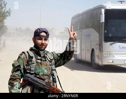 (180327) -- DAMAS, le 27 mars 2018 -- Un soldat syrien émet un signe de victoire alors qu'un bus de rebelles évacués quitte le point de rassemblement à la périphérie de la ville d'Arbeen, dans la capitale, la Ghouta orientale, en Syrie, le 26 mars 2018. Plus de 13 000 rebelles et leurs familles ont évacué les villes centrales de Damas, la capitale syrienne, dans la campagne de la Ghouta orientale au cours des trois derniers jours. )(jmmn) SYRIE-DAMAS-REBELLES-ÉVACUATION AmmarxSafarjalani PUBLICATIONxNOTxINxCHN Banque D'Images