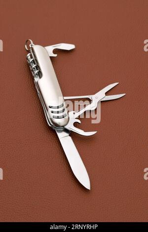 Gros plan photo de couteau suisse sur fond de cuir brun Banque D'Images