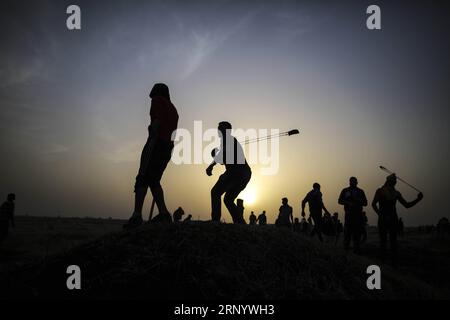 (180406) -- GAZA, 6 avril 2018 -- des manifestants palestiniens utilisent des frondes pour lancer des pierres sur les troupes israéliennes lors d'affrontements à la frontière Gaza-Israël, à l'est de la ville de Gaza, le 5 avril 2018. Au moins 18 Palestiniens ont été tués et plus de 1 200 autres blessés depuis vendredi dernier, lorsqu'une manifestation palestinienne massive a été lancée pour marquer la Journée de la terre palestinienne le long de la frontière entre Gaza et Israël. MIDEAST-GAZA-AFFRONTEMENTS WissamxNassar PUBLICATIONxNOTxINxCHN Banque D'Images