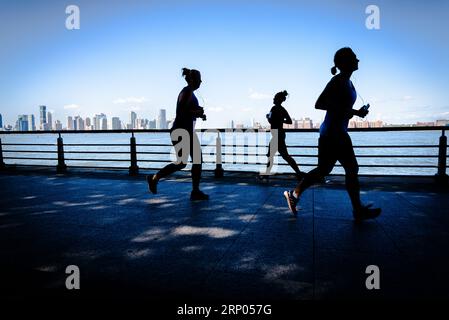 Des coureurs silhouettés le long de l'Hudson River sur le chemin Hudson River Greenway à Manhattan, New York, États-Unis. Banque D'Images