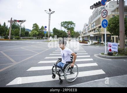 (180510) -- BEICHUAN, le 10 mai 2018 -- Zheng Haiyang, un survivant qui a perdu ses jambes dans le tremblement de terre de magnitude 8,0 de Wenchuan en 2008, déplace son fauteuil roulant pour traverser la route dans le nouveau comté de Beichuan, dans la province du Sichuan, au sud-ouest de la Chine, le 8 mai 2018. Il y a dix ans, Zheng, alors élève de 17 ans à l’école secondaire de Beichuan, a été extirpé 22 heures après avoir été pris au piège dans les décombres du bâtiment de l’école dans le comté de Beichuan. Beichuan a été l'une des régions les plus touchées lorsque le séisme catastrophique a frappé le comté de Wenchuan le 12 mai 2008. Zheng était un survivant du tremblement de terre qui a laissé plus Banque D'Images