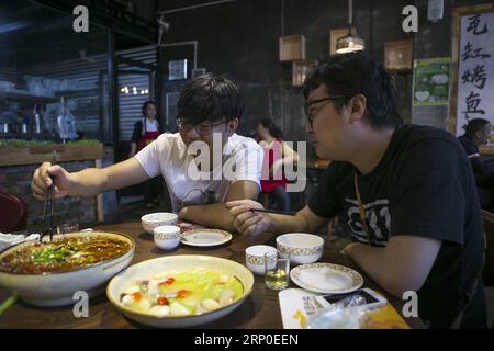 (180510) -- BEICHUAN, 10 mai 2018 -- Zheng Haiyang (L), survivant qui a perdu ses jambes dans le tremblement de terre de magnitude 8,0 de Wenchuan en 2008, prend un repas avec son ami dans un restaurant du nouveau comté de Beichuan, dans la province du Sichuan, au sud-ouest de la Chine, le 8 mai 2018. Il y a dix ans, Zheng, alors élève de 17 ans à l’école secondaire de Beichuan, a été extirpé 22 heures après avoir été pris au piège dans les décombres du bâtiment de l’école dans le comté de Beichuan. Beichuan a été l'une des régions les plus touchées lorsque le séisme catastrophique a frappé le comté de Wenchuan le 12 mai 2008. Zheng était un survivant du tremblement de terre que le Banque D'Images