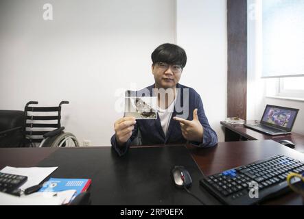 (180510) -- BEICHUAN, le 10 mai 2018 -- Zheng Haiyang, un survivant qui a perdu ses jambes dans le tremblement de terre de Wenchuan de magnitude 8,0 de 2008, montre sa photo sous des décombres dans son bureau dans la province du Sichuan du sud-ouest de la Chine, le 8 mai 2018. Il y a dix ans, Zheng, alors élève de 17 ans à l’école secondaire de Beichuan, a été extirpé 22 heures après avoir été pris au piège dans les décombres du bâtiment de l’école dans le comté de Beichuan. Beichuan a été l'une des régions les plus touchées lorsque le séisme catastrophique a frappé le comté de Wenchuan le 12 mai 2008. Zheng était un survivant du tremblement de terre qui a laissé plus de 80 000 personnes Banque D'Images