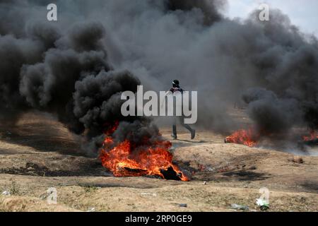 (180514) -- GAZA, 14 mai 2018 -- Un manifestant palestinien brûle des pneus lors d'affrontements avec les troupes israéliennes à Gaza, le 14 mai 2018.) (wtc) MIDEAST-GAZA-AFFRONTEMENTS Stringer PUBLICATIONxNOTxINxCHN Banque D'Images