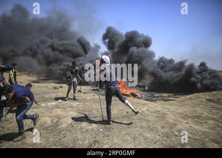 (180514) -- GAZA, 14 mai 2018 -- Un manifestant palestinien utilise une fronde pour lancer des pierres sur les troupes israéliennes lors d'affrontements, avant le jour de la Nakba, ou jour de la catastrophe, près de la frontière à l'est de la ville de Gaza, le 14 mai 2018.) (hy) MIDEAST-GAZA-AFFRONTEMENTS WissamxNassar PUBLICATIONxNOTxINxCHN Banque D'Images