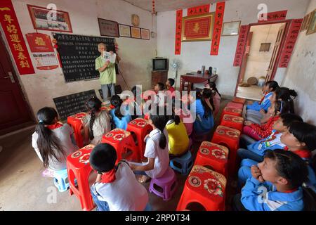 (180524) -- NANCHANG, 24 mai 2018 -- Miao Yanxiang lit un rapport sur les bonnes actions pour les enfants au poste de garde pour enfants laissés-pour-compte à son domicile dans la ville de Shibu, ville de Nanchang dans la province de Jiangxi dans l'est de la Chine, le 23 mai 2018. Miao, âgé de plus de 70 ans, a créé un poste de garde pour les enfants laissés derrière lui dans sa propre maison en 2009, où il a fourni une place gratuite pour les enfants pour faire leurs devoirs et étudier après l'école. Ayant reçu plus de 3 000 enfants au cours des neuf dernières années, Miao est satisfait de son travail bénévole et voit les progrès des enfants. (ZWX) CHINA-JIANGXI-LEFT-BEHIND CHILDREN-EL Banque D'Images