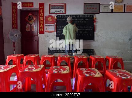 (180524) -- NANCHANG, 24 mai 2018 -- Miao Yanxiang écrit de vieux dictons sur le tableau noir du poste de garde pour enfants laissés derrière lui à son domicile de la ville de Shibu, ville de Nanchang dans la province de Jiangxi dans l'est de la Chine, le 23 mai 2018. Miao, âgé de plus de 70 ans, a créé un poste de garde pour les enfants laissés derrière lui dans sa propre maison en 2009, où il a fourni une place gratuite pour les enfants pour faire leurs devoirs et étudier après l'école. Ayant reçu plus de 3 000 enfants au cours des neuf dernières années, Miao est satisfait de son travail bénévole et voit les progrès des enfants. (ZWX) CHINA-JIANGXI-LEFT-BEHIND ENFANTS-ELDER C. Banque D'Images