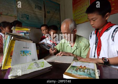 (180524) -- NANCHANG, 24 mai 2018 -- des enfants empruntent des livres au poste de garde pour enfants laissés derrière eux au domicile de Miao Yanxiang dans la ville de Shibu, ville de Nanchang dans la province de Jiangxi dans l est de la Chine, 23 mai 2018. Miao, âgé de plus de 70 ans, a créé un poste de garde pour les enfants laissés derrière lui dans sa propre maison en 2009, où il a fourni une place gratuite pour les enfants pour faire leurs devoirs et étudier après l'école. Ayant reçu plus de 3 000 enfants au cours des neuf dernières années, Miao est satisfait de son travail bénévole et voit les progrès des enfants. (ZWX) CHINA-JIANGXI-LEFT-BEHIND CHILDREN-OLD CARE(CN) PENGXZH Banque D'Images