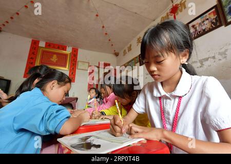 (180524) -- NANCHANG, 24 mai 2018 -- les enfants font leurs devoirs au poste de garde pour enfants laissés derrière eux dans la maison de Miao Yanxiang dans la ville de Shibu, ville de Nanchang dans la province de Jiangxi dans l est de la Chine, 23 mai 2018. Miao, âgé de plus de 70 ans, a créé un poste de garde pour les enfants laissés derrière lui dans sa propre maison en 2009, où il a fourni une place gratuite pour les enfants pour faire leurs devoirs et étudier après l'école. Ayant reçu plus de 3 000 enfants au cours des neuf dernières années, Miao est satisfait de son travail bénévole et voit les progrès des enfants. (ZWX) CHINA-JIANGXI-LEFT-BEHIND CHILDREN-OLD CARE(CN) PENGXZHAOZ Banque D'Images