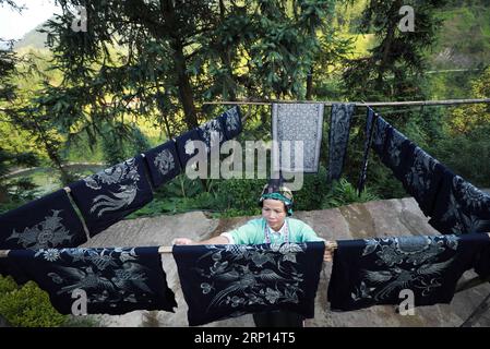 (180609) -- DANZHAI, le 9 juin 2018 -- Une femme du groupe ethnique miao sèche des produits batik dans la ville de Yangwu, dans le comté de Danzhai, dans le sud-ouest de la Chine, dans la province du Guizhou, le 8 juin 2018. L artisanat batik du peuple Miao est l un des patrimoines intangibles nationaux de la Chine. En tant que principal site d'héritage de l'artisanat batik du peuple Miao, le village de Jijia Miao de la ville de Yangwu a un bon nombre d'excellents artisans, mais le trafic gênant avait entravé la vente de produits batik à l'extérieur avant 2017. Avec l'amélioration croissante de la circulation et de l'aide du gouvernement local et des bénévoles depuis 2017, les gens Banque D'Images