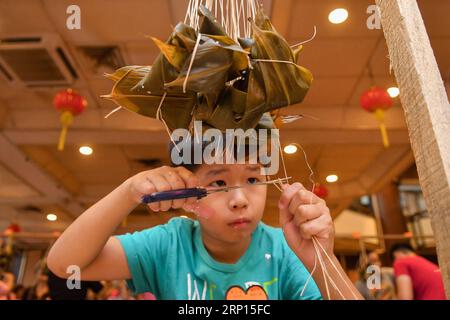 (180610) -- KUALA LUMPUR, le 10 juin 2018 -- Un garçon fabrique Zongzi, une boulette en forme de pyramide faite de riz gluant enveloppé dans des feuilles de bambou ou de roseau, lors d'un concours pour célébrer le prochain festival des bateaux-dragons à Kuala Lumpur, Malaisie, le 10 juin 2018. )(cl) MALAYSIA-KUALA LUMPUR-ZONGZI-WRAPPING-CONTEST ChongxVoonxChung PUBLICATIONxNOTxINxCHN Banque D'Images