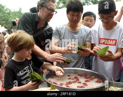 (180616) -- PÉKIN, 16 juin 2018 -- le touriste américain Morgan Perkins (2e L) et son fils Quinn (1e L) apprennent à fabriquer Zongzi, une boulette en forme de pyramide faite de riz gluant enveloppé dans des feuilles de bambou ou de roseau, lors d'une activité pour célébrer le prochain festival des bateaux-dragons au Beijing Stone Carving Art Museum à Beijing, capitale de la Chine, le 16 juin 2018. (Wyo) CHINA-DRAGON BOAT FESTIVAL-CELEBRATIONS (CN) LuoxXiaoguang PUBLICATIONxNOTxINxCHN Banque D'Images