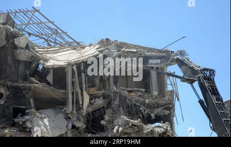 (180619) -- DAMAS, le 19 juin 2018 -- une excavatrice démolit un bâtiment en grande partie détruit dans la ville de Harasta, dans la Ghouta orientale, près de Damas, capitale de la Syrie, le 19 juin 2018. Le gouvernement syrien a commencé à enlever les décombres et à démolir des bâtiments en grande partie détruits à Harasta en prélude au processus de reconstruction dans la région. SYRIE-DAMAS-HARASTA-RUBBLE-REMOVAL AmmarxSafarjalani PUBLICATIONxNOTxINxCHN Banque D'Images