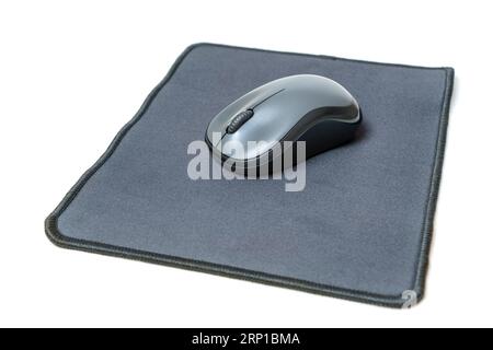 Souris d'ordinateur reposant sur le tapis de souris neuf isolé sur fond blanc. Banque D'Images