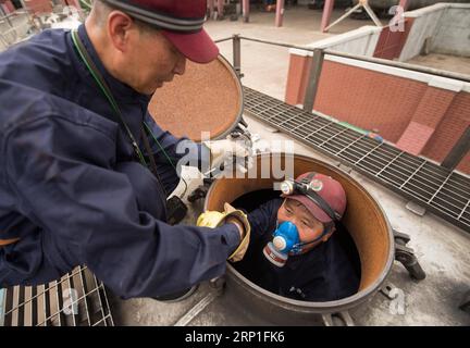 (180703) -- CHANGCHUN, 3 juillet 2018 -- Yu Guodong(R) sort d'un pétrolier vide après l'avoir nettoyé dans la ville de Jilin, dans la province de Jilin, au nord-est de la Chine, le 2 juillet 2018. Yu Guodong, un préposé à l'entretien des chemins de fer, est chargé du nettoyage des wagons-citernes du train de marchandises transportant des liquides combustibles. Le nettoyage de chaque citerne prend 30 minutes. Les ouvriers de maintenance travaillent à l'intérieur des pétroliers, où la température atteint parfois 60 degrés Celsius en été. Vêtu de vêtements ignifuges, Yu doit nettoyer plus de 20 wagons-citernes par jour dans la chaleur brûlante de l'été, pour assurer la sécurité des chemins de fer Banque D'Images