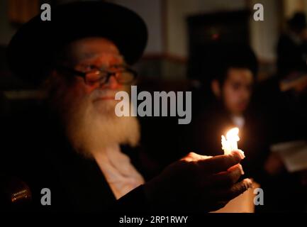 (180722) -- JÉRUSALEM, 22 juillet 2018 -- les juifs ultra-orthodoxes utilisent des bougies pour lire le livre d'Eicha (Livre des Lamentations) lors du jeûne annuel de Tisha B AV (neuvième d'AV) et d'un jour commémoratif dans le quartier ultra-orthodoxe de Mea Shearim à Jérusalem, le 21 juillet 2018. Gil Cohen Magen)(dtf) MIDEAST-JERUSALEM-TISHA B AV guoyu PUBLICATIONxNOTxINxCHN Banque D'Images