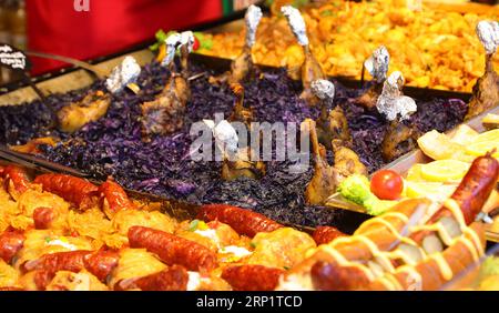 Plat typique de la cuisine d'Europe centrale avec des cuisses de poulet rôties au chou violet et des saucisses de Francfort avec des pommes de terre au festival du village Banque D'Images