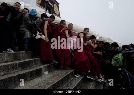 (180811) -- LHASSA, 11 août 2018 -- des gens portent une immense peinture Thangka au monastère de Drepung à Lhassa, capitale de la région autonome du Tibet du sud-ouest de la Chine, 11 août 2018. Les célébrations du traditionnel festival de Shoton, ou festival du yaourt, ont commencé à Lhassa samedi. Cette année, l'événement mettra en vedette le soleil traditionnel des cérémonies du Bouddha, avec d'énormes peintures Thangka portant l'image du Bouddha exposées sur les collines près des monastères de Drepung et de sera, ainsi que des spectacles d'opéra tibétain, des spectacles d'équitation et un spectacle de costumes ethniques.) (ZYD) CHINE-TIBET-SHOTON FE Banque D'Images