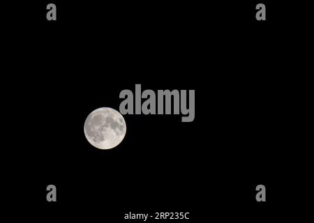 Pleine lune dans un ciel sombre. La lune super bleue du 30 au 31 août a été largement photographiée dans le monde entier. Dans le sud de l'Angleterre, j'étais limité par mon emplacement dans une zone bâtie, dans les photos que je pouvais prendre. La lune n'était pas visible à mon emplacement jusqu'à environ 2200 heures le 30 août. À 0100 heures le 31, le ciel s'est couvert de nuages et a ainsi terminé une soirée frustrante car le temps optimal d'observation de la lune sur la côte sud de l'Angleterre, était de 0235 heures. La prochaine lune de ce genre sera en 2037. Banque D'Images