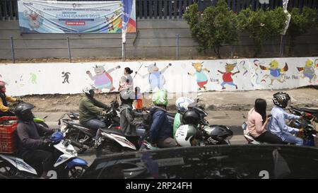 (180817) -- JAKARTA, août 17,2018 -- les motocyclistes passent devant les peintures des mascottes des Jeux asiatiques à Jakarta le 16 août 2018. Le 18 août sera marqué par la cérémonie d'ouverture des 18e Jeux asiatiques à Jakarta, Indonésie. (SP)INDONÉSIE-JAKARTA-JEUX ASIATIQUES-VIE QUOTIDIENNE LANXHONGGUANG PUBLICATIONXNOTXINXCHN Banque D'Images
