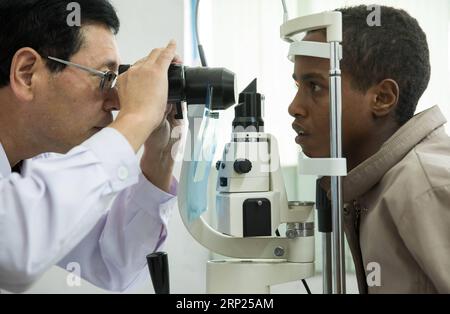 (180819) -- ADDIS ABABA, 19 août 2018 -- le médecin chinois Li Xiushan vérifie les yeux d'un garçon à l'hôpital de l'amitié Ethio-Chine, situé à Akaki, à la périphérie de la capitale éthiopienne Addis Ababa, Éthiopie, 17 août 2018. Le 20e groupe de l'équipe médicale chinoise, qui comprend 16 professionnels de la santé, est basé à l'hôpital Tirunesh-Pékin, également connu sous le nom d'hôpital de l'amitié Ethio-Chine. La Chine a publié la première Journée des travailleurs médicaux le 19 août.) ETHIOPIE-ADDIS-ABEBA-ÉQUIPE MÉDICALE CHINOISE LYUXSHUAI PUBLICATIONXNOTXINXCHN Banque D'Images