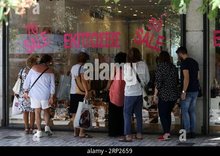 (180820) -- ATHÈNES, 20 août 2018 -- les gens regardent les marchandises à travers les vitrines pendant la période des soldes d'été, à Athènes, Grèce, 20 août 2018. La sortie lundi de la Grèce des programmes de renflouement introduits il y a huit ans pour éviter un effondrement financier et restaurer la croissance de l'économie endettée est un premier pas important, mais aucune raison de célébrer, a déclaré à Xinhua l'ancien Premier ministre grec George Papandreou. (wtc) GRÈCE-ATHÈNES-SORTIE DES RENFLOUEMENTS MariosxLolos PUBLICATIONxNOTxINxCHN Banque D'Images