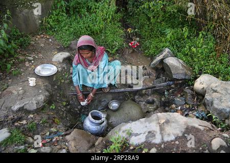 (180824) -- SRINAGAR, 24 août 2018 -- Une femme cachemirienne lave ses ustensiles devant une conduite d'eau cassée dans un village du district de Budgam, à environ 40 km au sud-ouest de la ville de Srinagar, capitale estivale du Cachemire contrôlé par les Indiens, 24 août 2018.) (dtf) CACHEMIRE-SRINAGAR-VIE QUOTIDIENNE CONTRÔLÉE PAR L'INDE JavedxDar PUBLICATIONxNOTxINxCHN Banque D'Images