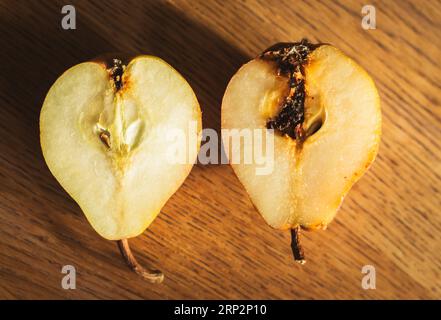 Poires endommagées sur la table en bois. Pois avec mouche sur la planche à découper. Bon et mauvais. Agriculture d'automne. Concept de différence. Nourriture crue. Tranches de poire douce. Banque D'Images