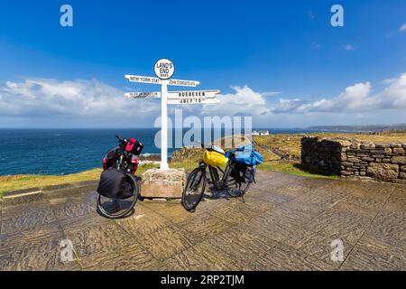 Deux e-bikes au célèbre panneau indiquant New York, John o' Groats et les îles Scilly, LANd's End, Lands End, Penzance, Penwith Peninsula, Cornwall Banque D'Images