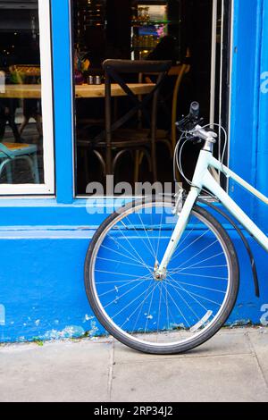 Vélo bleu clair appuyé contre un mur bleu à Édimbourg. Prise de vue verticale. Banque D'Images