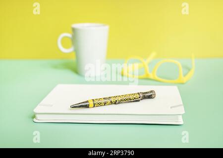 Une image lumineuse et colorée d'un bloc-notes avec un stylo et des lunettes jaunes Banque D'Images