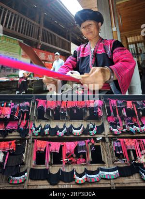 (181001) -- NANNING, 1 octobre 2018 -- la photo combinée montre Pan Jifeng, l'héritière représentative du costume du groupe ethnique Yao, manipulant un morceau de tissu, le 3 juillet 2014 (dessus), et deux femmes séchant des vêtements sur un bâtiment en bois, le 2 juillet 2014, dans le canton de Longji du comté de Longsheng, dans la région autonome de Guangxi Zhuang, dans le sud de la Chine. Le costume du groupe ethnique Yao est un élément inscrit au patrimoine culturel immatériel national. Guangxi compte maintenant 50 éléments répertoriés comme héritages culturels immatériels nationaux, et 618 éléments répertoriés comme héritages culturels immatériels au niveau régional autonome. (Gxn) CHINE- Banque D'Images