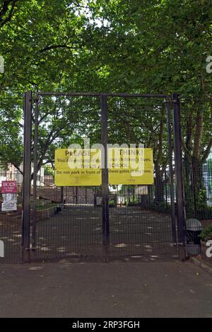 Parking de l'école avec haute clôture et portes fermées avec des panneaux jaunes sans parking. Réfléchissez ! Panneau aux portes de l'école, Bristol centre, Angleterre. 2022 Banque D'Images