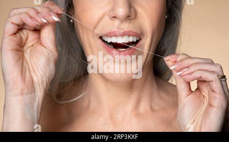 Sourire parfait, soins dentaires et concept de traitement buccal. Plan rapproché d'une femme âgée méconnaissable utilisant du fil dentaire Banque D'Images