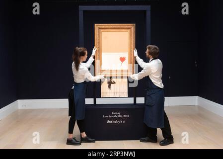 Actualités Themen der Woche KW41 Actualités Bilder des Tages (181012) -- LONDRES, 12 octobre 2018 -- les membres du personnel de Sotheby s présentent Banksy s Love is in the Bin à Londres, Grande-Bretagne, le 12 octobre 2018. Initialement intitulé Girl with Balloon , le Street artist britannique Banksy a fait autodétruire sa peinture le 5 octobre, quelques instants après qu'elle ait été vendue aux enchères pour 1,042 millions de livres sterling (1,37 millions de dollars américains) chez Sotheby s à Londres. BRITAIN-LONDON-BANKSY-LOVE EST DANS LE BIN RAYXTANG PUBLICATIONXNOTXINXCHN Banque D'Images