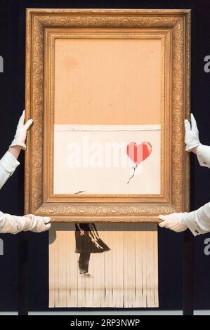 (181012) -- LONDRES, 12 octobre 2018 -- les membres du personnel de Sotheby s présentent Banksy s Love is in the Bin à Londres, Grande-Bretagne, le 12 octobre 2018. Initialement intitulé Girl with Balloon , le Street artist britannique Banksy a fait autodétruire sa peinture le 5 octobre, quelques instants après qu'elle ait été vendue aux enchères pour 1,042 millions de livres sterling (1,37 millions de dollars américains) chez Sotheby s à Londres. BRITAIN-LONDON-BANKSY-LOVE EST DANS LE BIN RAYXTANG PUBLICATIONXNOTXINXCHN Banque D'Images