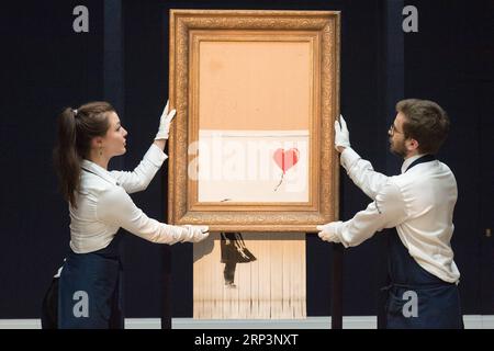 (181012) -- LONDRES, 12 octobre 2018 -- les membres du personnel de Sotheby s présentent Banksy s Love is in the Bin à Londres, Grande-Bretagne, le 12 octobre 2018. Initialement intitulé Girl with Balloon , le Street artist britannique Banksy a fait autodétruire sa peinture le 5 octobre, quelques instants après qu'elle ait été vendue aux enchères pour 1,042 millions de livres sterling (1,37 millions de dollars américains) chez Sotheby s à Londres. BRITAIN-LONDON-BANKSY-LOVE EST DANS LE BIN RAYXTANG PUBLICATIONXNOTXINXCHN Banque D'Images