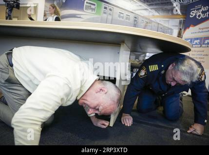 (181019) -- VANCOUVER, 19 oct. 2018 (Xinhua) -- des gens se mettent à couvert sous la table lors de l'exercice de grand tremblement de terre à Vancouver, Canada, le 18 octobre 2018. Environ 910 000 personnes ont participé à l'exercice annuel Great Shakeout Earthquake en Colombie-Britannique au Canada. Exercice simulé mené par Canada Line - système de trains sans conducteur et contrôlé par ordinateur de Vancouver, pour mettre en pratique la façon dont les exploitants de transport en commun et les résidents réagissent après l'alerte de déclenchement du système d'alerte précoce aux tremblements de terre. (Xinhua/Liang Sen) (qxy) CANADA-VANCOUVER-EARTHQUAKE-DRILL PUBLICATIONxNOTxINxCHN Banque D'Images