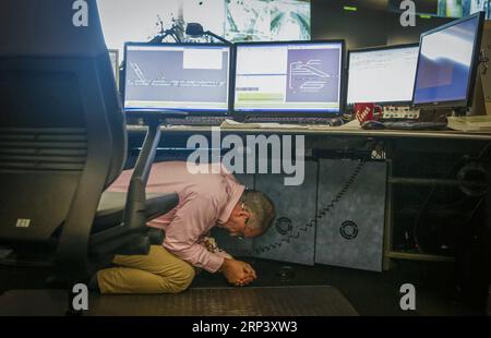 (181019) -- VANCOUVER, 19 oct. 2018 (Xinhua) -- un membre du personnel se cache sous la table à l'intérieur de la salle de contrôle de Canada Line lors de l'exercice Great Shakeout Earthquake à Vancouver, Canada, le 18 octobre 2018. Environ 910 000 personnes ont participé à l'exercice annuel Great Shakeout Earthquake en Colombie-Britannique au Canada. Exercice simulé mené par Canada Line - système de trains sans conducteur et contrôlé par ordinateur de Vancouver, pour mettre en pratique la façon dont les exploitants de transport en commun et les résidents réagissent après l'alerte de déclenchement du système d'alerte précoce aux tremblements de terre. (Xinhua/Liang Sen) (qxy) CANADA-VANCOUVER-EARTHQUAK Banque D'Images