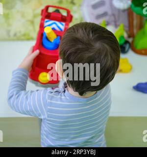 Bébé joue avec des jouets dans la maternelle. Un petit garçon heureux dans la salle de jeux. Enfant âgé d'un an neuf mois Banque D'Images