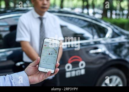 (181020) -- PÉKIN, 20 octobre 2018 -- Un travailleur de Shouqi Limousine & chauffeur montre son application mobile pour le transport en voiture à Shenzhen, dans la province du Guangdong du sud de la Chine, le 7 avril 2017. Si vous veniez à Pékin, capitale de la Chine, il y a 40 ans, vous avez probablement été frappé par la mer des vélos dans les rues, un phénomène unique qui a valu à la Chine le titre de royaume des vélos. À cette époque, les Chinois ordinaires ne pouvaient pas se permettre de voitures et peu de gens pouvaient voyager par avion, sans parler des voyages fréquents sur de longues distances. Les trains, le moyen de transport le plus courant à l'époque, étaient toujours bourrés dans la boursouflure Banque D'Images